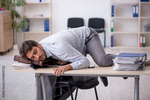 Young male employee in oversleeping concept photo