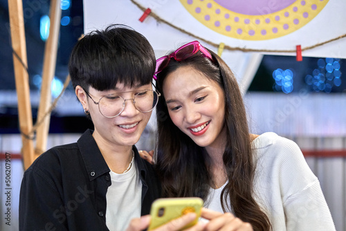 Lesbian couple looking at a mobile in the middle of a night urban fair photo