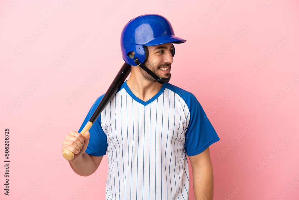 Baseball player with helmet and bat isolated on pink background looking side Baseball player with helmet and bat isolated on pink background looking side