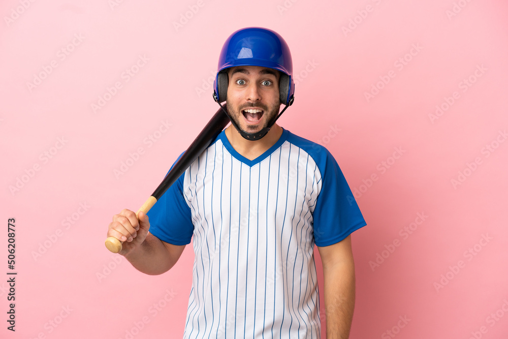 Baseball player with helmet and bat isolated on pink background with surprise facial expression