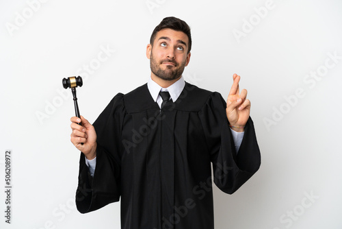 Judge caucasian man isolated on white background with fingers crossing and wishing the best