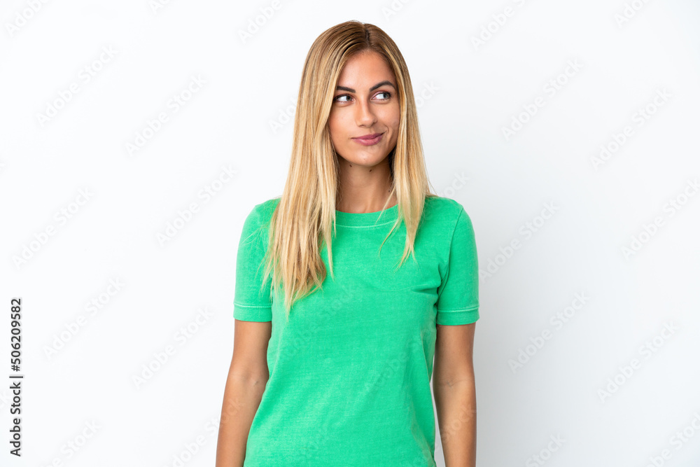 Blonde Uruguayan girl isolated on white background having doubts while looking side Blonde Uruguayan girl isolated on white background having doubts while looking side