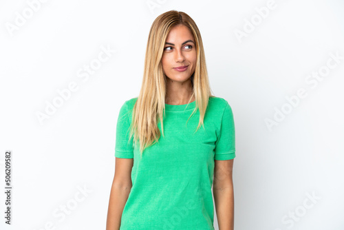 Blonde Uruguayan girl isolated on white background having doubts while looking side