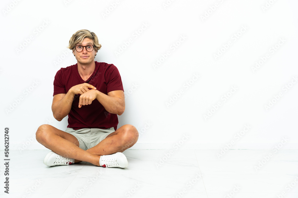 Fototapeta premium Young English man sitting on the floor making the gesture of being late