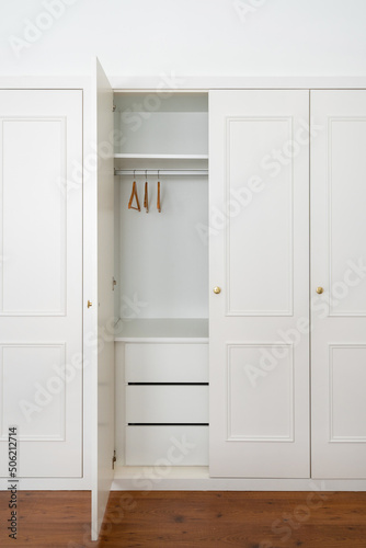 Empty white wardrobe with hangers in room