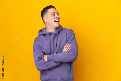 Young caucasian man isolated on yellow background happy and smiling