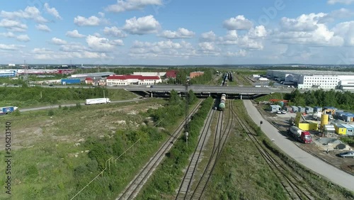 Aerial view of Industrial area with highway, buildings and railway tracks. Cars drive along the highway, trains stand on the railroad. summer sunny day
