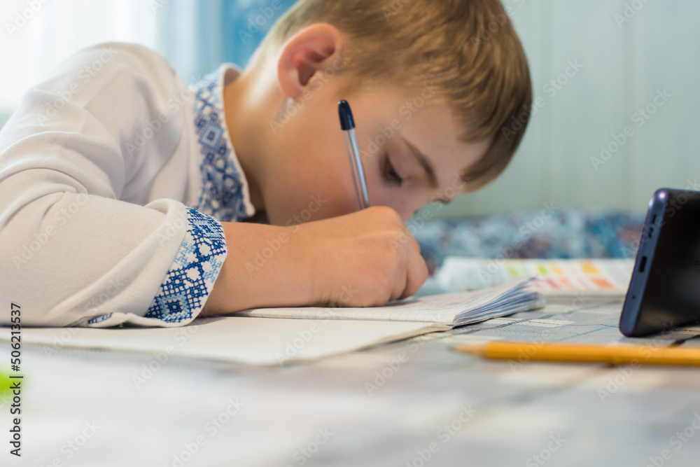 Ukrainian little boy studies online via smartphone Ukrainian little boy studies online via smartphone