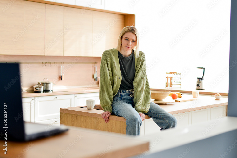 Portrait of young woman sitting on kitchen table Portrait of young woman sitting on kitchen table