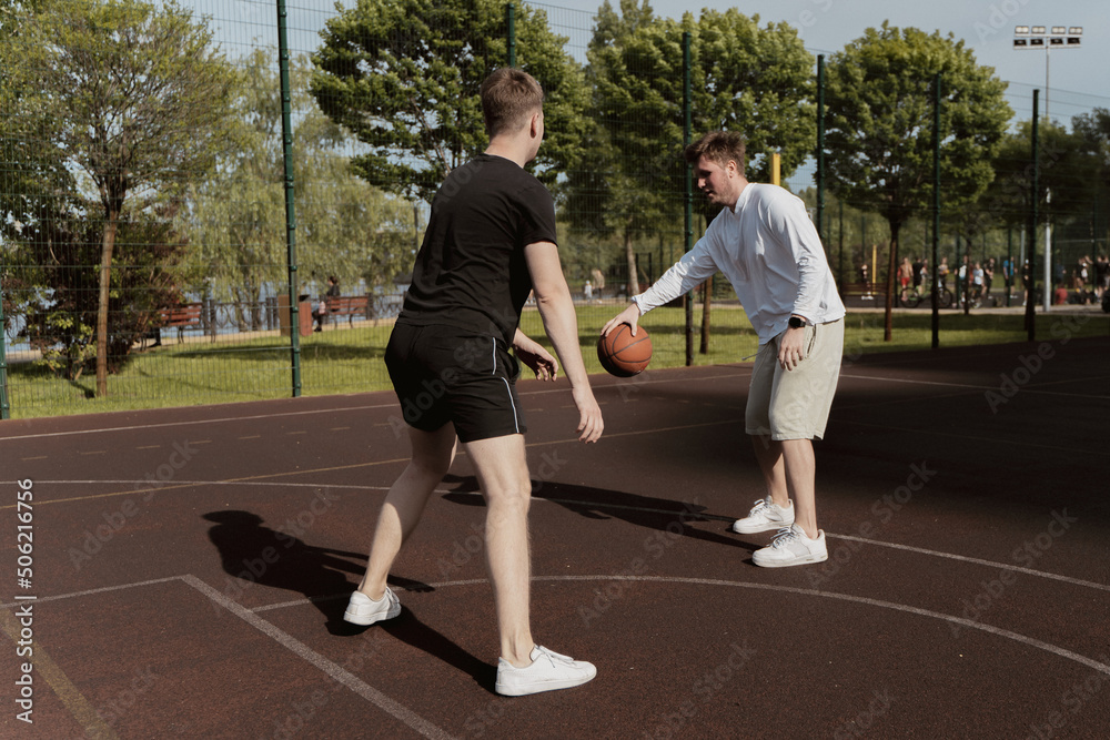 two guys play basketball outdoors on the court