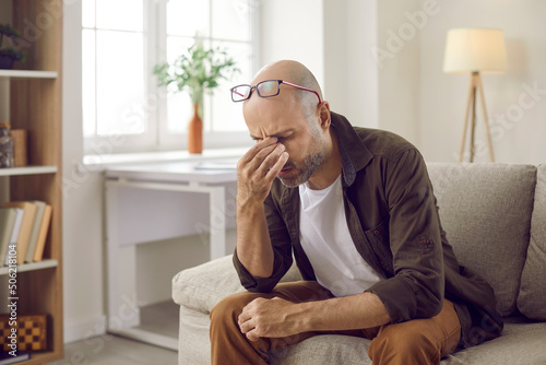 Canvas Print Unhealthy man feel stressed suffer from migraine or headache at home