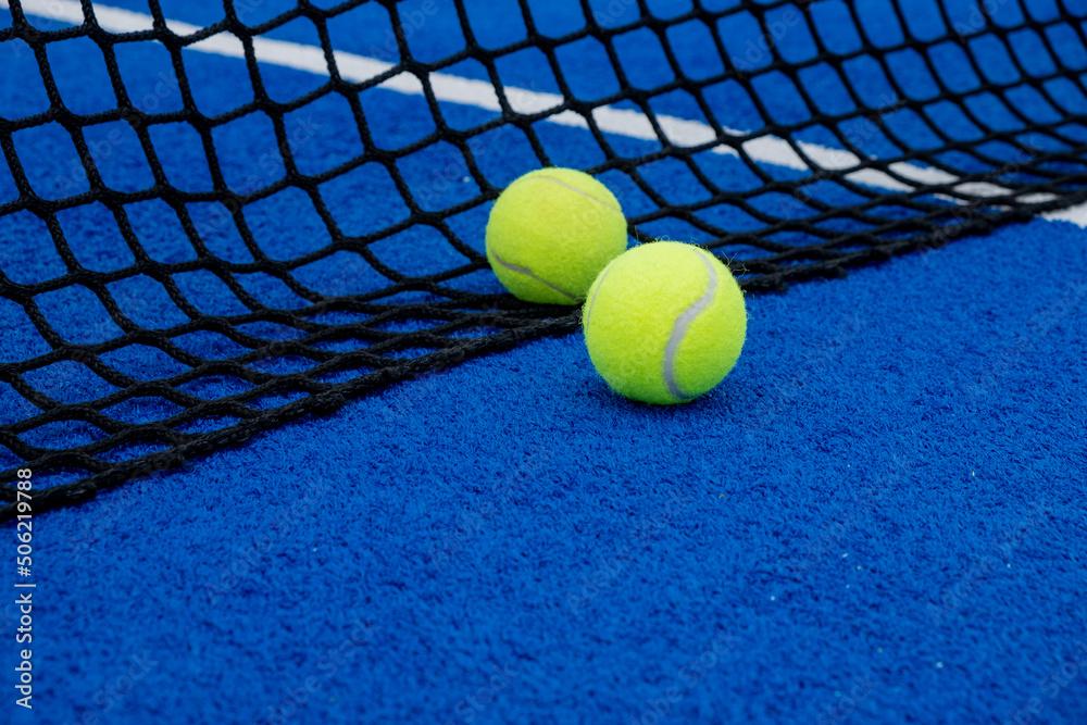 Blue artificial grass paddle tennis court two balls near the net