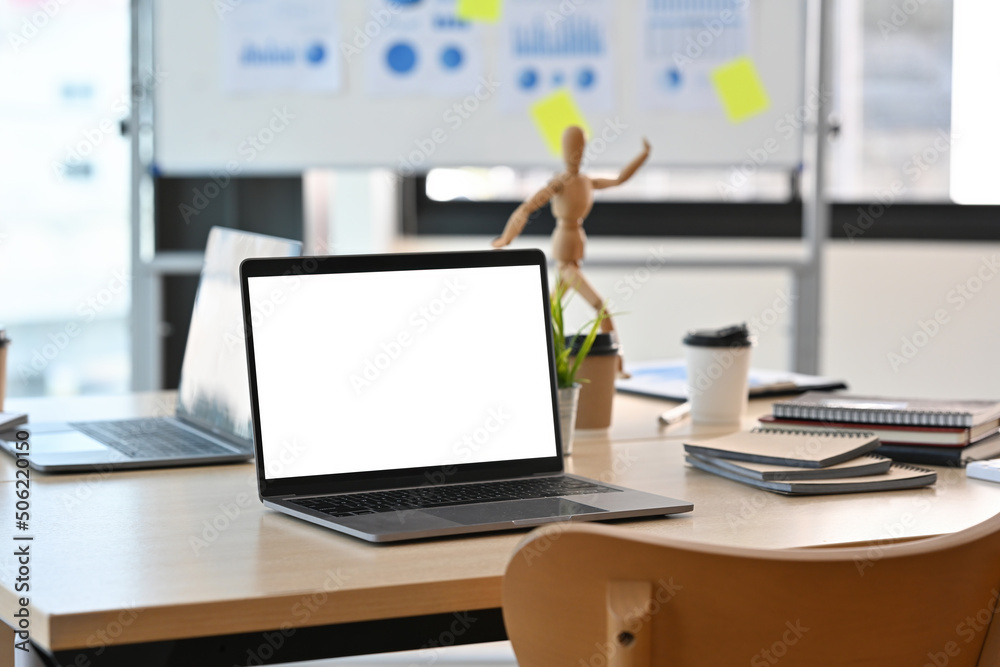 A blank white screen laptop computer setting on the wooden desk with the modern interior office decoration. Business and financial concepts. A blank white screen laptop computer setting on the wooden desk with the modern interior office decoration. Business and financial concepts.