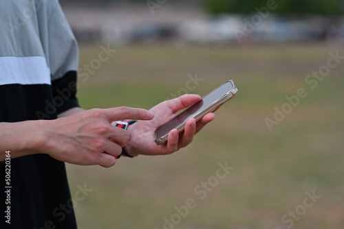 Close up male hands holding a smartphone and try to use it over an outdoor view as a background. Business and technology concepts.