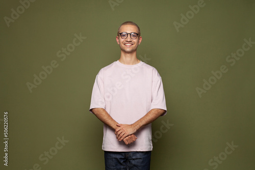 Bilde på lerret Happy creative man wearing t-shirt and glasses smiling standing on khaki green s