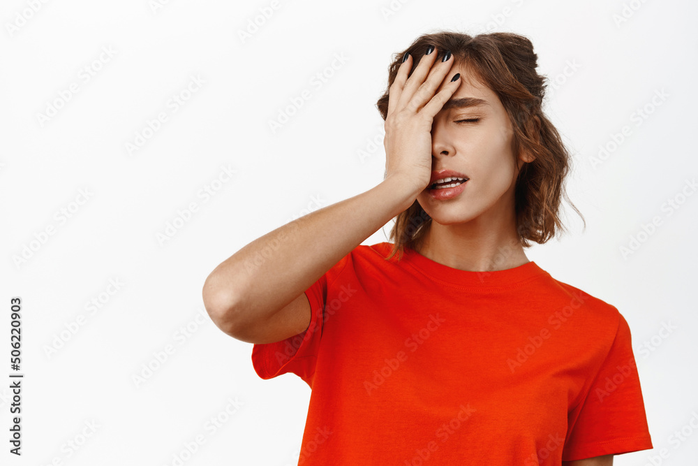 Facepalm girl. Disappointed young woman looking tired, slap face with hand, standing distressed and upset, white studio background Facepalm girl. Disappointed young woman looking tired, slap face with hand, standing distressed and upset, white studio background