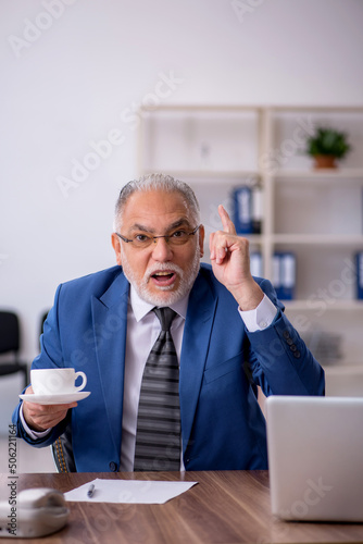 Old male employee drinking coffee during break