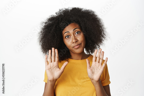 Close up portrait of african american woman shows her clean and empty hands, stop block gesture, enough, staring skeptical at camera, white background