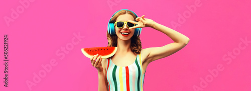 Summer colorful portrait of cheerful happy smiling young woman model posing in headphones listening to music with juicy slice of watermelon on pink background, blank copy space for advertising text
