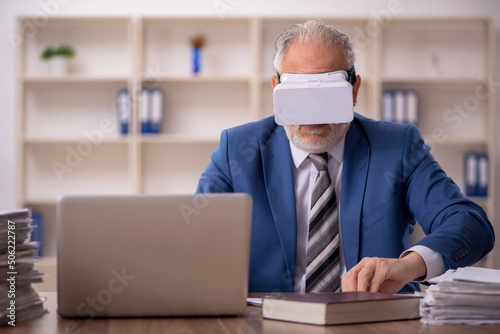 Aged male employee wearing virtual glasses in the office