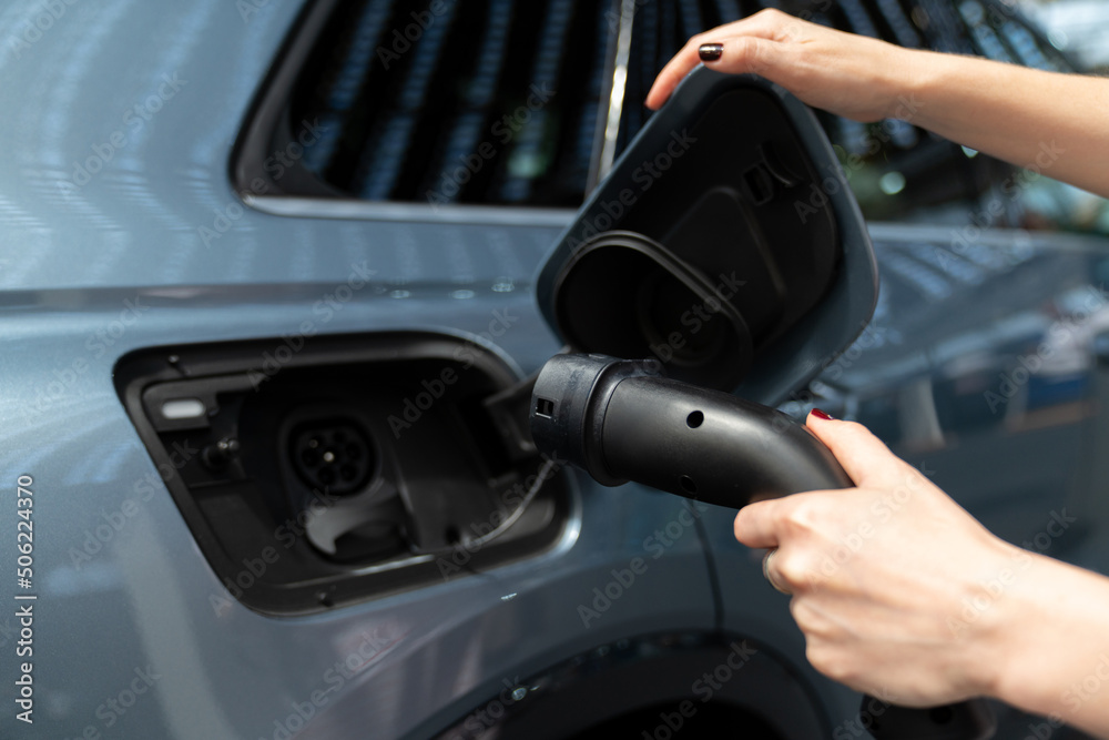 Woman holding plug of electric car charging station 