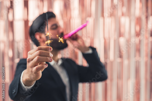 Happy beaded man holding Bengal lights and blowing a whistle over pink background. High quality photo