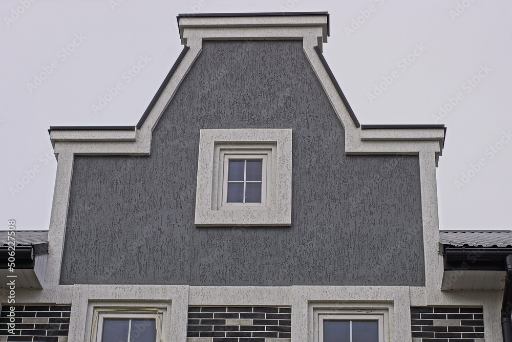 gray attic of a private house with one small white window against a sky