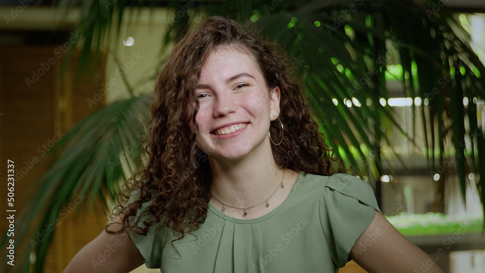 Close-up of a young very cheerful woman with brown, curly hair looking into the camera. Portrait of a girl Close-up of a young very cheerful woman with brown, curly hair looking into the camera. Portrait of a girl