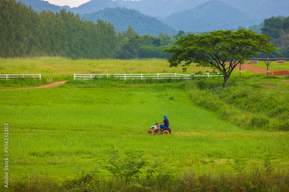 Driving in the green fields behind the mountains with bright blue skies.