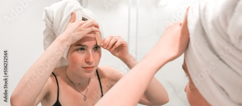 Beauty concept. Wellness, taking care yourself. Portrait beautiful woman looking in the mirror in the bathroom.Beautiful girl bath towel her head, taking care of herself, gouache massage, mask, spa