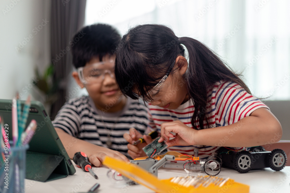 two Asian children having fun learning coding together, learning remotely at home, STEM science, homeschooling education, fun social distancing, isolation, new normal concept