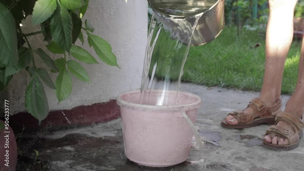 A man draws water from a well, turns the handle and a bucket of water rises