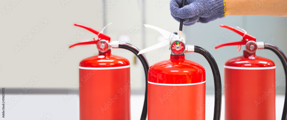 Obraz premium Fire extinguisher has hand engineer inspection checking pressure gauges to prepare fire equipment for protection and prevent emergency and safety rescue and alarm system training concept.