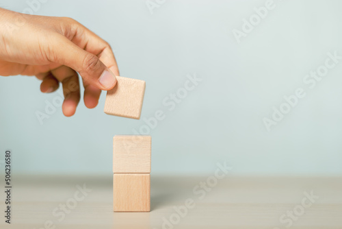concept of grow success. hand holding and stacking wooden block cube step of business growth success.