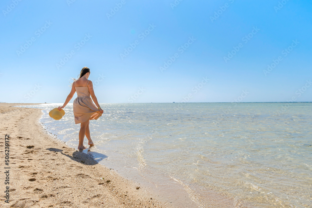 Young adult female woman person with hat enjoy relaxing on sea,walk along ocean beach,coast in luxury resort,looking on blue clear water.Summer travel tropical recreational vacation tourism concept Young adult female woman person with hat enjoy relaxing on sea,walk along ocean beach,coast in luxury resort,looking on blue clear water.Summer travel tropical recreational vacation tourism concept