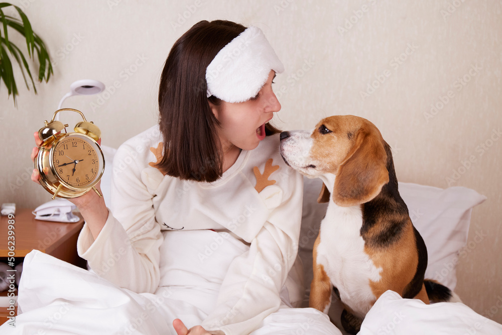 A teenage girl and a beagle dog look at each other in surprise. The girl has