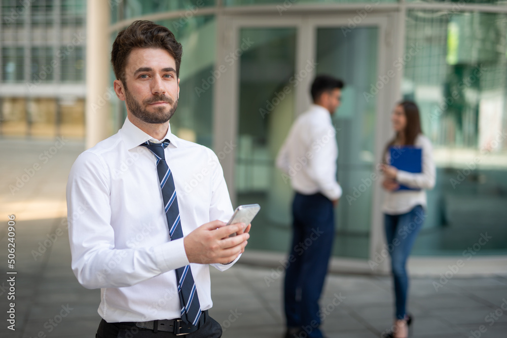 Businessman using his cellphone in front of a group of colleagues, teamwork concept