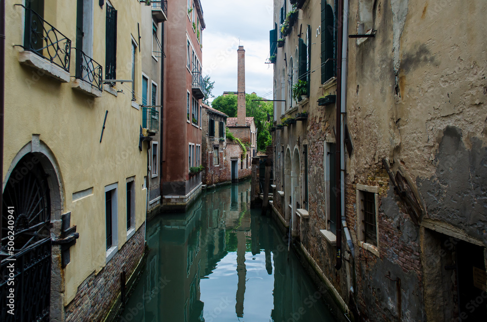 La ciminiera di una fornace si riflette in un canale della Giudecca a Venezia