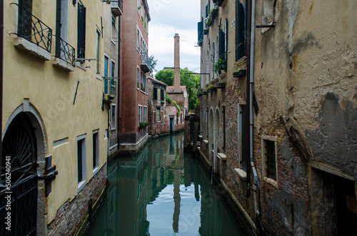 La ciminiera di una fornace si riflette in un canale della Giudecca a Venezia