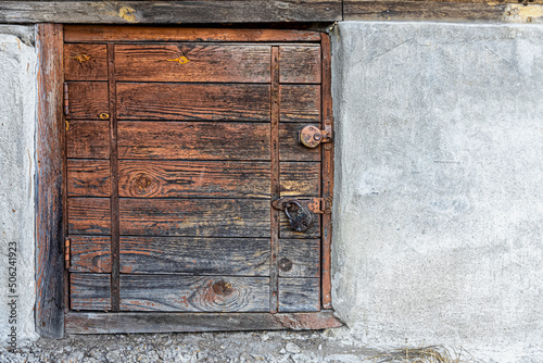 Small wooden door in the concrete base of the house