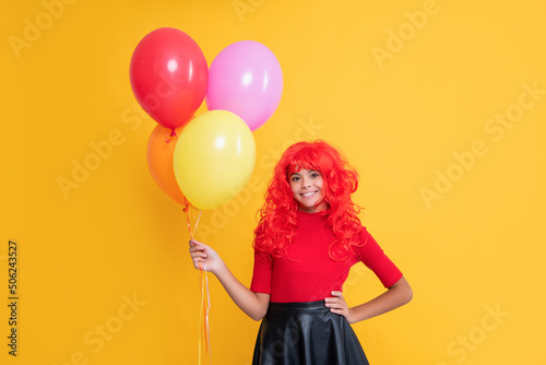 cheerful teen girl with party balloon on yellow background