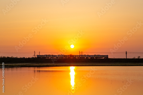 田んぼに映える夕日と羽越線の電車