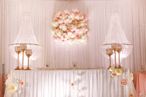 festive wedding table decoration with crystal chandeliers, golden candlesticks, candles and white pink flowers . stylish wedding day.