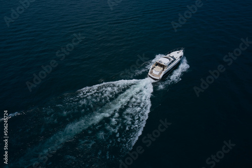 large yacht top view. Large boat at high speed on dark blue water and top view. Aerial view of a boat in motion in dark water. Boats top white waves on dark water.