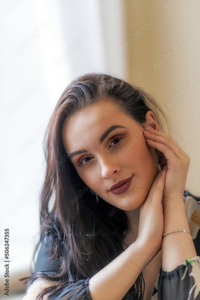 Portrait of attractive dark haired girl posing with hands on chin. Vertically. Portrait of attractive dark haired girl posing with hands on chin. Vertically.