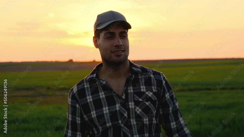 Handsome Farmer putting On his Cap at Sunset. Positive young farmer looking at agricultural field during scenic sunset. High quality 4k footage Handsome Farmer putting On his Cap at Sunset. Positive young farmer looking at agricultural field during scenic sunset. High quality 4k footage
