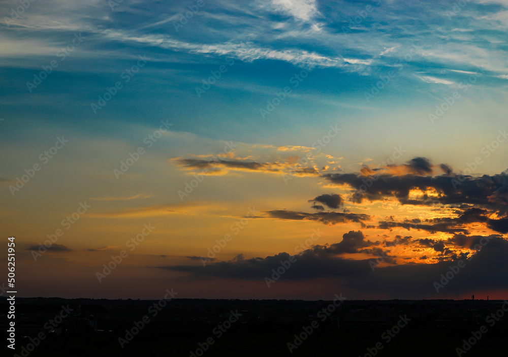 Evening sky. The rays of the sun break through the clouds above the horizon. Abstract background. Sunset.