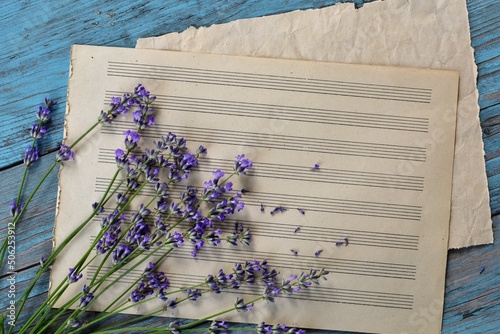 Blank sheet music with lavender flowers on vintage blue  wooden background closeup. Happy Birthday, Valentine's day, wedding, Mother's Day invitation greeting card concept.