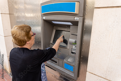 Elderly woman using an ATM in the street