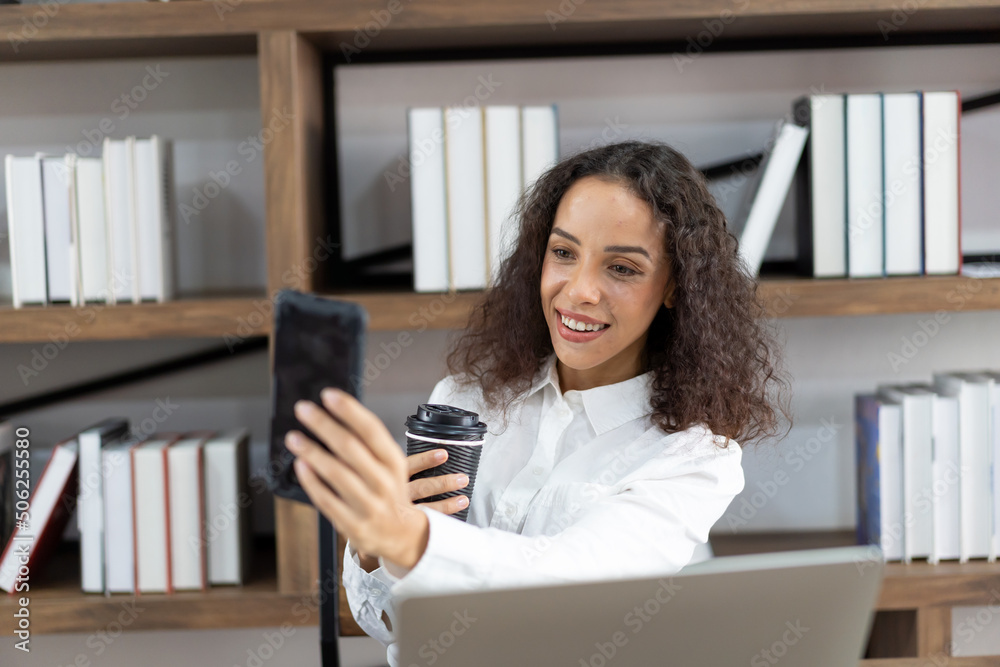 Smile business woman working with laptop computer, using mobile phone and holding black coffee on hand in the office. Smile business woman working with laptop computer, using mobile phone and holding black coffee on hand in the office.